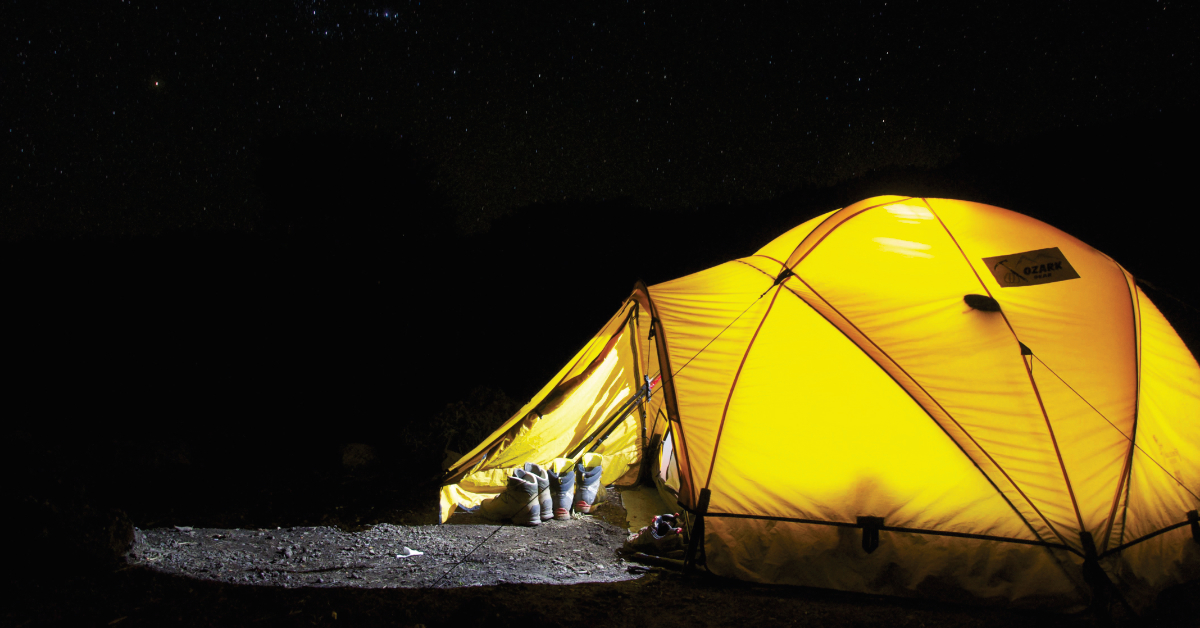 Beleuchtetes Zelt in der Nacht mit Stiefel im Eingang Beleuchtetes Zelt in der Nacht mit Stiefel im Eingang